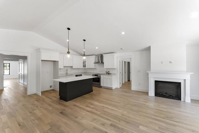 kitchen featuring light wood-type flooring, wall chimney exhaust hood, decorative light fixtures, a center island, and white cabinetry