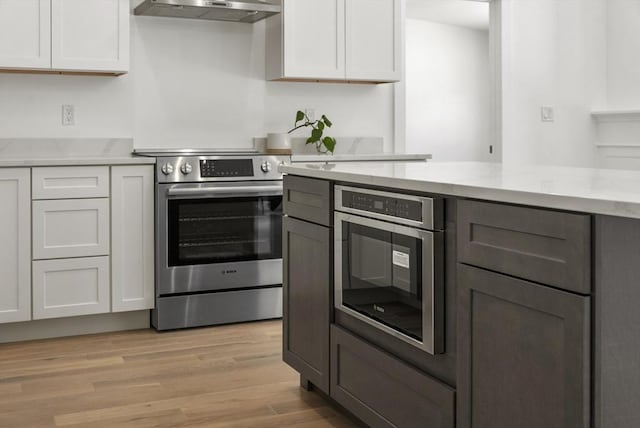 kitchen featuring white cabinets, electric range, ventilation hood, and light hardwood / wood-style flooring