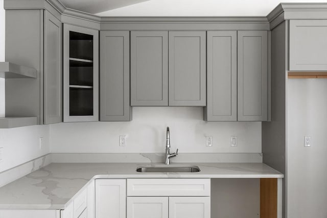 kitchen featuring gray cabinetry, light stone countertops, and sink