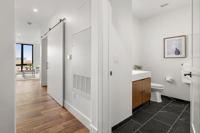 bathroom with visible vents, toilet, vanity, and wood finished floors