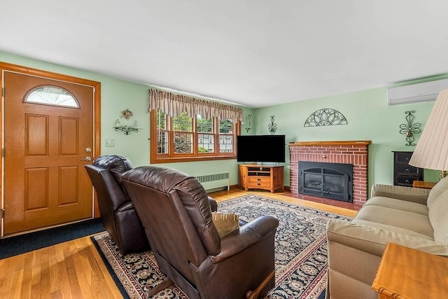 23 Willard St, Dedham, MA 02026 - living room with an AC wall unit, wood finished floors, radiator heating unit, and a brick fireplace