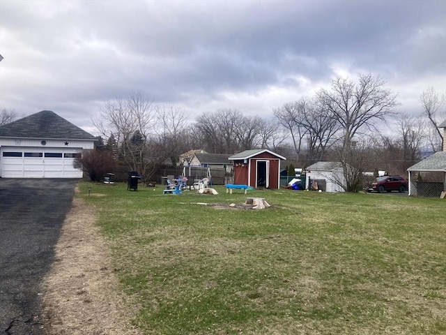 view of yard featuring a garage, fence, a storage unit, and an outdoor structure