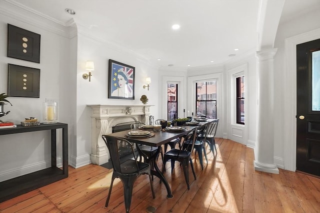 dining room with light wood-style flooring, decorative columns, and crown molding