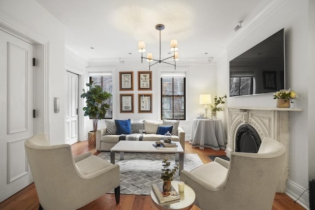 living room featuring a fireplace, ornamental molding, wood finished floors, a chandelier, and baseboards