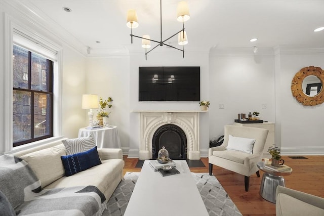 living room featuring baseboards, a fireplace with flush hearth, ornamental molding, and wood finished floors