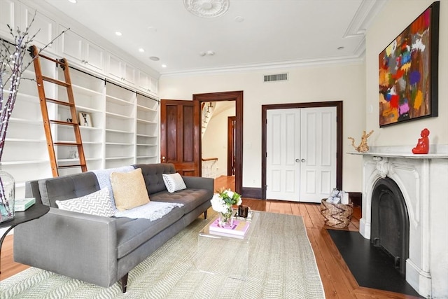 living area with a fireplace, crown molding, recessed lighting, visible vents, and hardwood / wood-style floors