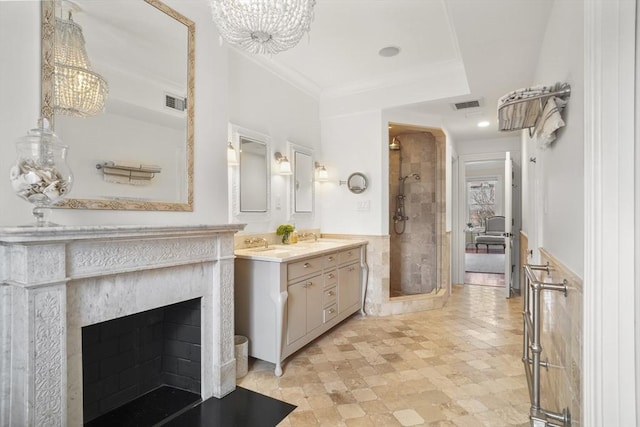 bathroom featuring a wainscoted wall, vanity, visible vents, a shower stall, and crown molding