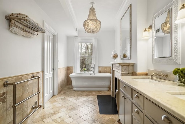 bathroom featuring double vanity, a wainscoted wall, ornamental molding, a freestanding bath, and a sink