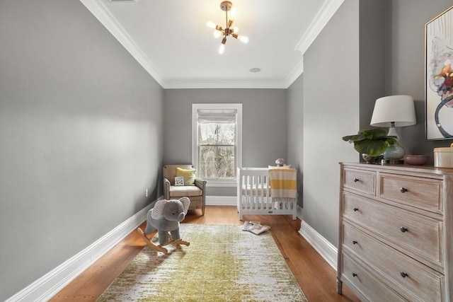 bedroom featuring a chandelier, ornamental molding, wood finished floors, and baseboards