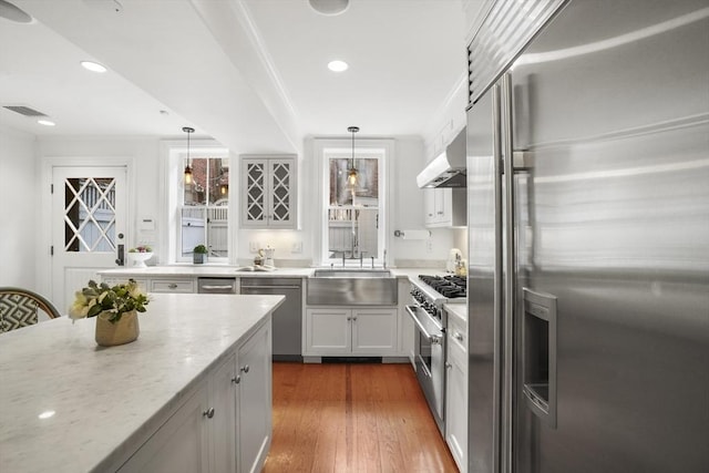 kitchen featuring light stone counters, under cabinet range hood, visible vents, high quality appliances, and dark wood finished floors