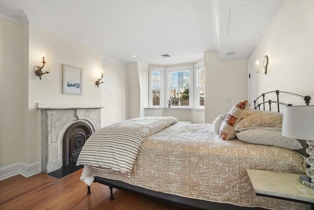 bedroom with a fireplace with flush hearth, baseboards, and wood finished floors