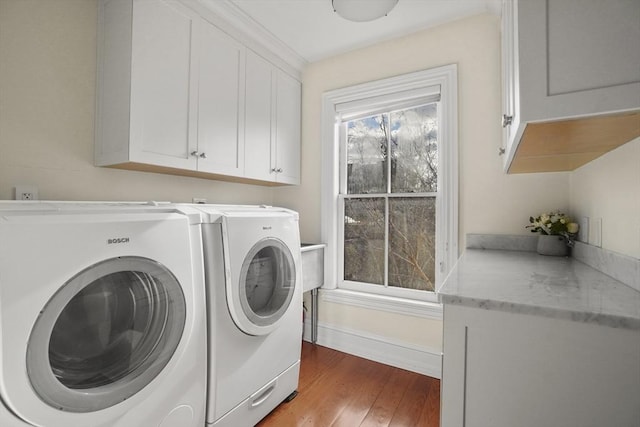 laundry area with independent washer and dryer, wood finished floors, cabinet space, and baseboards