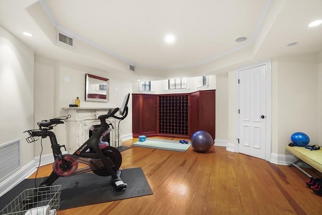 exercise room with wood-type flooring, visible vents, and baseboards