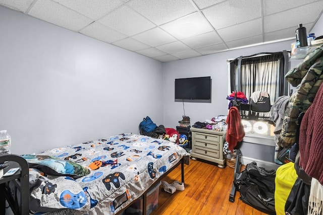 bedroom with a drop ceiling and wood-type flooring