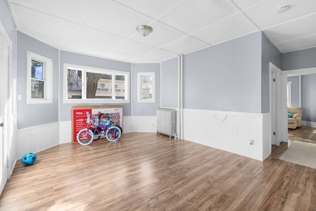 interior space featuring radiator heating unit, a drop ceiling, and hardwood / wood-style flooring