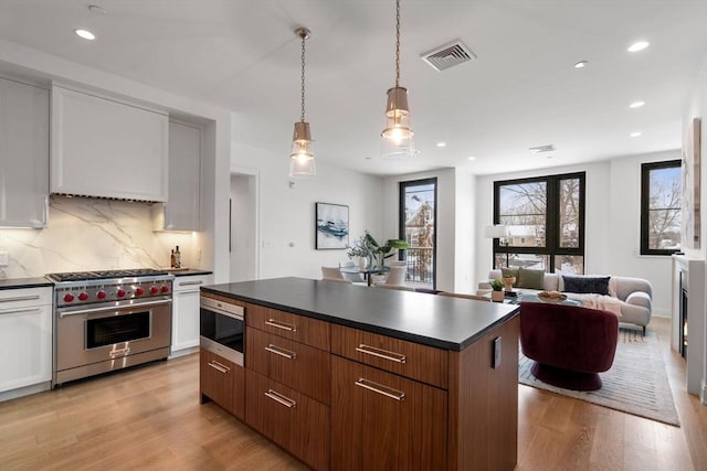 kitchen featuring light wood-style floors, dark countertops, luxury stove, and visible vents