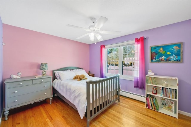 bedroom with light hardwood / wood-style flooring, ceiling fan, and baseboard heating