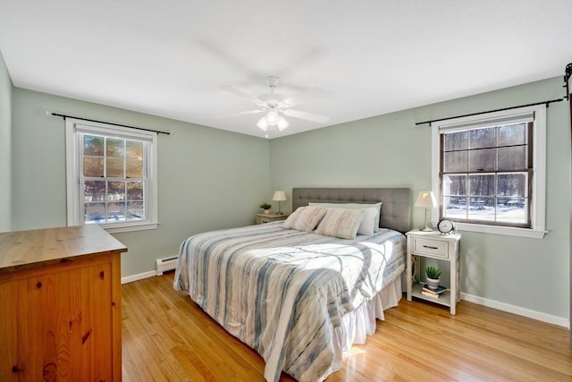 bedroom featuring multiple windows, a baseboard radiator, ceiling fan, and light wood-type flooring