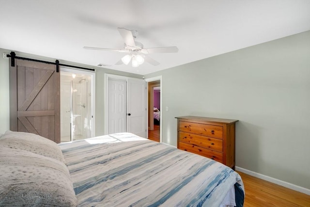 bedroom featuring wood-type flooring, a closet, ceiling fan, and a barn door