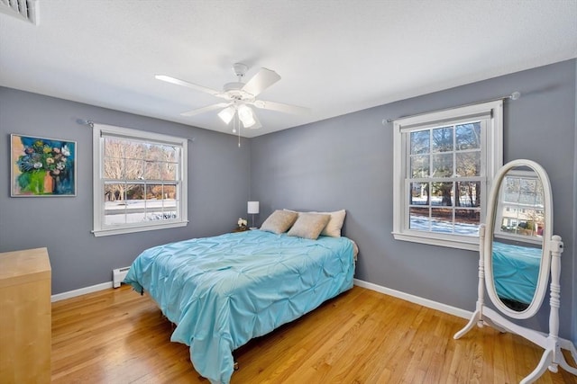 bedroom featuring ceiling fan, light hardwood / wood-style floors, and a baseboard radiator