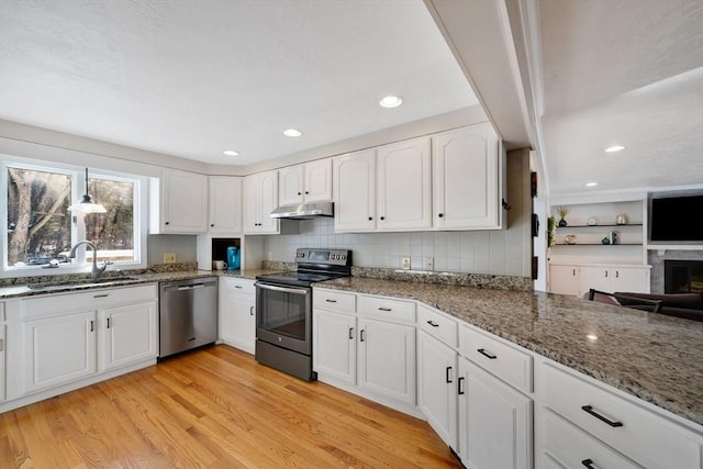 kitchen with sink, white cabinetry, light hardwood / wood-style flooring, dark stone countertops, and stainless steel appliances