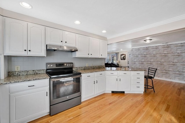 kitchen featuring light hardwood / wood-style flooring, white cabinets, a kitchen bar, stainless steel range with electric cooktop, and kitchen peninsula