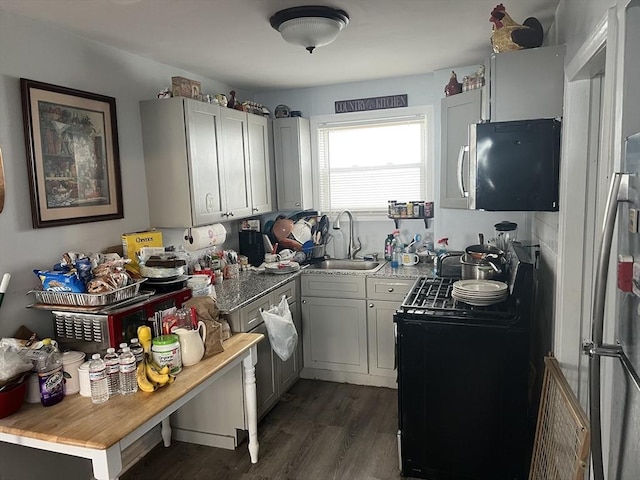 kitchen with a sink, black range with gas stovetop, dark wood-style floors, and stainless steel microwave