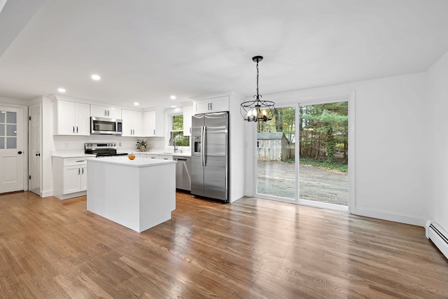 kitchen with decorative light fixtures, stainless steel appliances, light wood-type flooring, and plenty of natural light