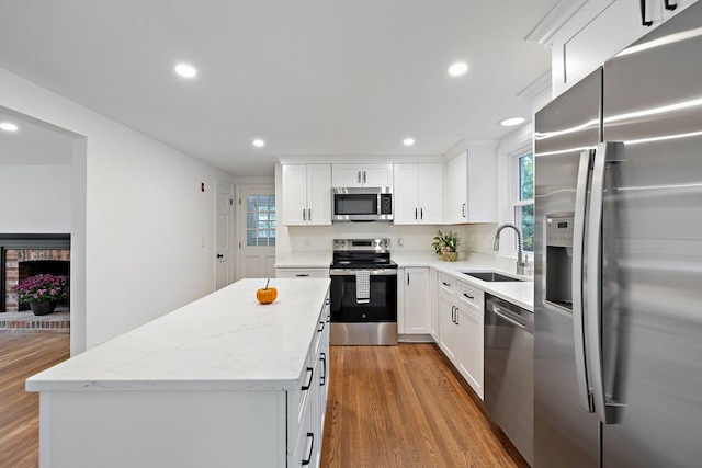 kitchen with a kitchen island, dark wood-type flooring, stainless steel appliances, sink, and white cabinetry