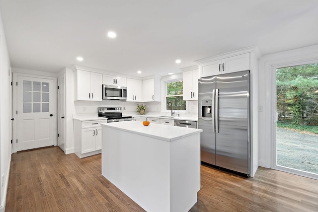 kitchen featuring a kitchen island, stainless steel appliances, sink, white cabinetry, and dark hardwood / wood-style flooring