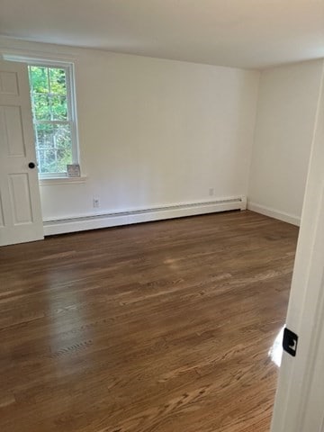 unfurnished room with dark hardwood / wood-style floors and a baseboard radiator