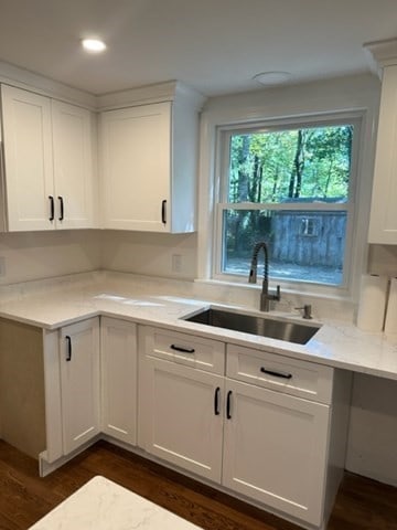 kitchen featuring light stone counters, sink, white cabinetry, and dark wood-type flooring