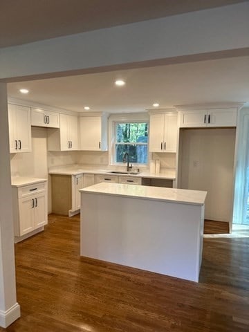 kitchen featuring dark wood-type flooring, sink, a kitchen island, and white cabinets