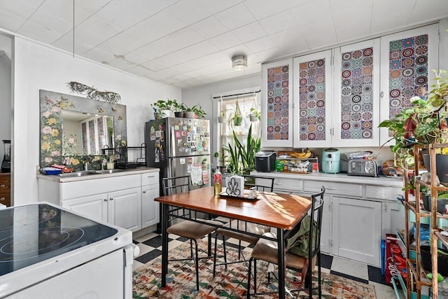 kitchen with white cabinets, white range with electric stovetop, sink, and stainless steel refrigerator