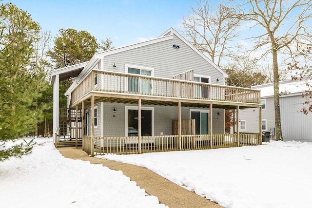 snow covered back of property featuring a deck