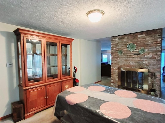 bedroom featuring a textured ceiling, light colored carpet, and a fireplace