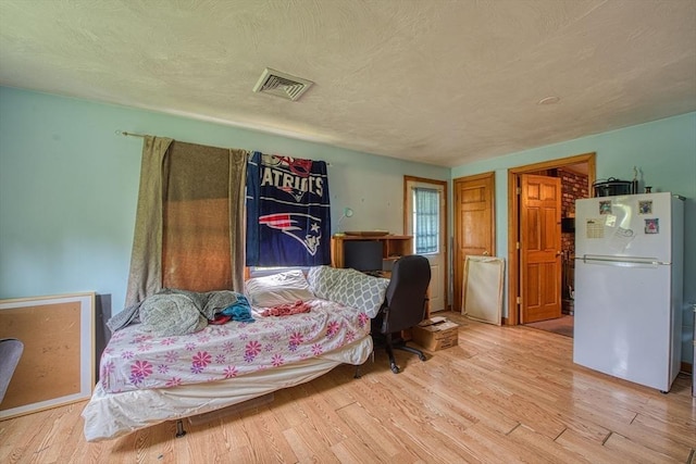 bedroom featuring freestanding refrigerator and wood finished floors