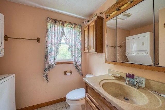 half bath with stacked washer and clothes dryer, toilet, vanity, and tile patterned floors