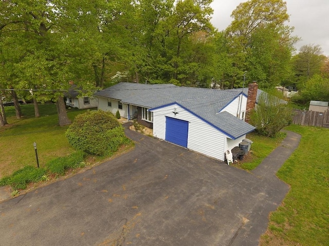 view of front facade with an attached garage, driveway, and a chimney