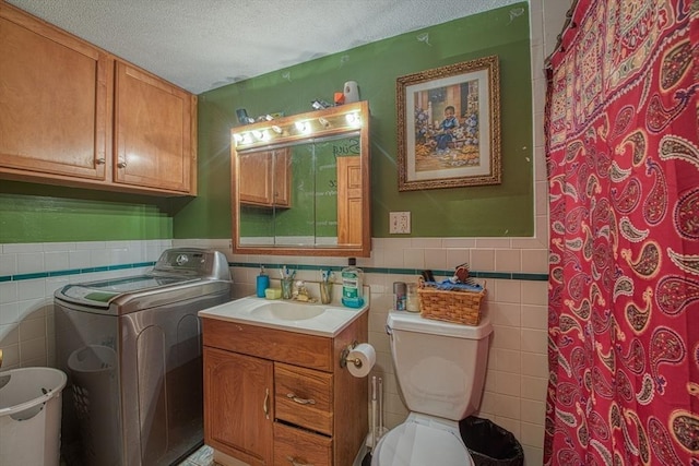 full bath featuring tile walls, washer / dryer, a wainscoted wall, toilet, and a textured ceiling