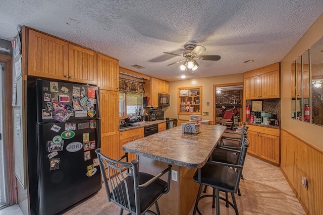kitchen with black appliances, a kitchen island, ceiling fan, a kitchen bar, and a textured ceiling