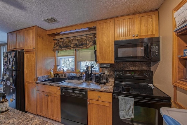 kitchen featuring black appliances, a sink, dark countertops, a textured ceiling, and brown cabinetry