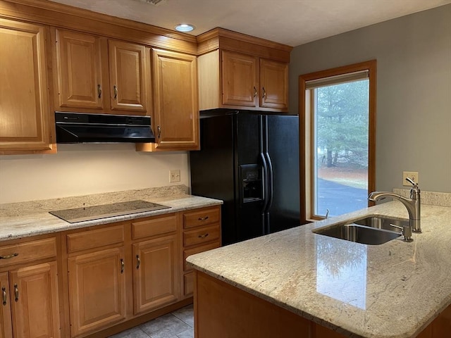 kitchen with sink, light stone counters, light tile patterned flooring, a center island, and black appliances