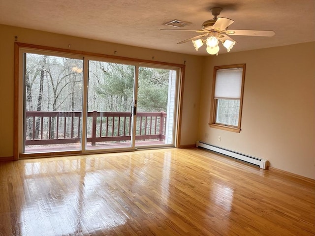 spare room with light wood-type flooring, ceiling fan, and baseboard heating