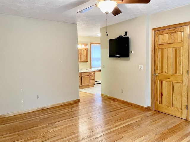 empty room with light wood-type flooring, ceiling fan, and a textured ceiling