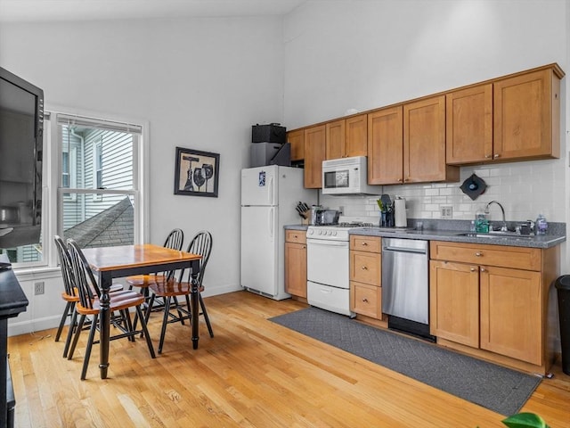 19 Tufts St, Somerville, MA 02145 - kitchen with white appliances, a sink, a high ceiling, tasteful backsplash, and light wood-style flooring