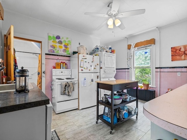19 Tufts St, Somerville, MA 02145 - kitchen with white appliances, stacked washer and clothes dryer, radiator heating unit, a ceiling fan, and wainscoting