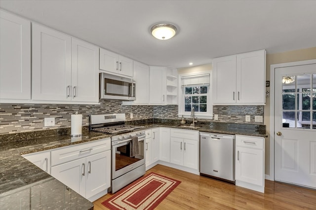 kitchen featuring white cabinetry, sink, tasteful backsplash, appliances with stainless steel finishes, and light wood-type flooring