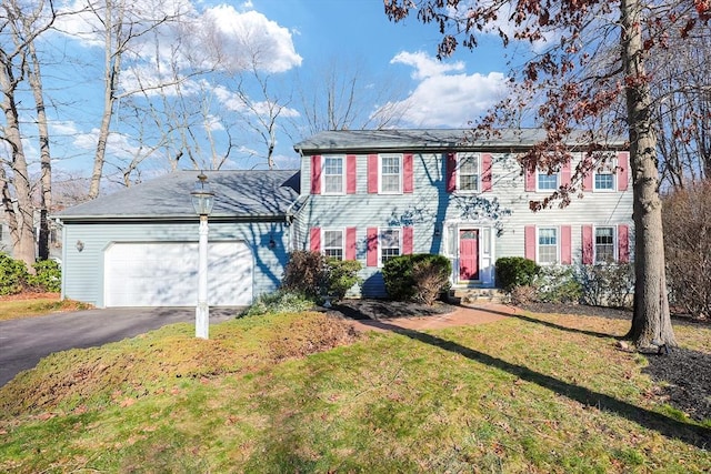 colonial-style house featuring a garage and a front lawn