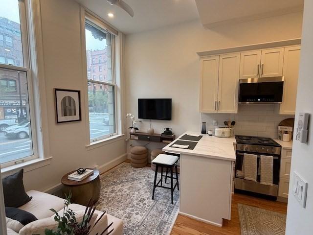 kitchen featuring light wood finished floors, backsplash, a healthy amount of sunlight, and stainless steel appliances